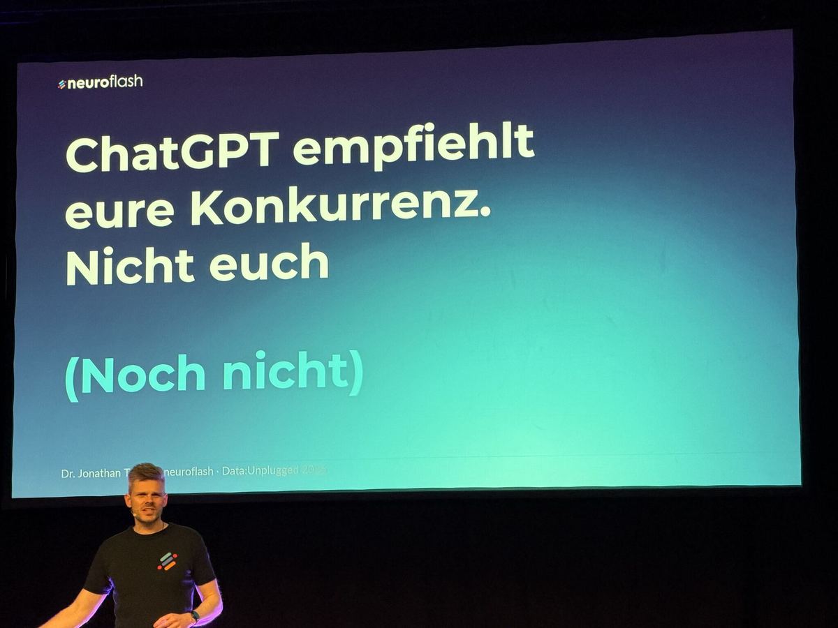Keynote-Folie „ChatGPT empfiehlt eure Konkurrenz. Nicht euch. (Noch nicht)“, Dr. Jonathan Mall auf der Bühne darunter